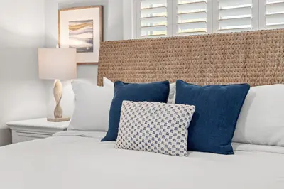a bed with blue and white pillows on it at Blue Tide Hideaway - Golf Cart, Sznl Hot Tub, Pets OK, FREE Daily Activities, & More! in Panama City