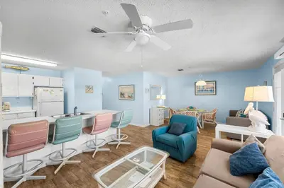 a living room with blue walls and a ceiling fan at Peachtree Place Ii C202 in Panama City Beach