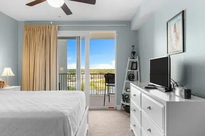 a bedroom with a bed and a television and a balcony at Laketown Wharf #1232 in Panama City Beach
