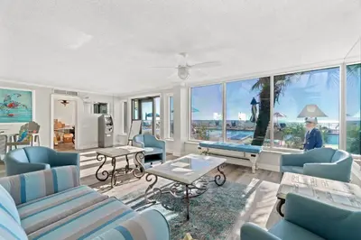 a living room with blue chairs and a large window at Regency Towers #0307 in Panama City Beach