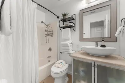 a bathroom with a sink and a toilet and a mirror at Sunset Haus in Panama City Beach