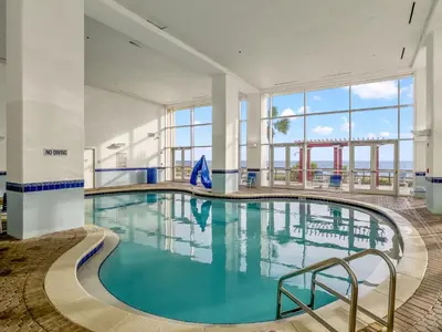 a pool with blue water in a building with large windows at Majestic Beach Towers #2-1203 in Panama City Beach
