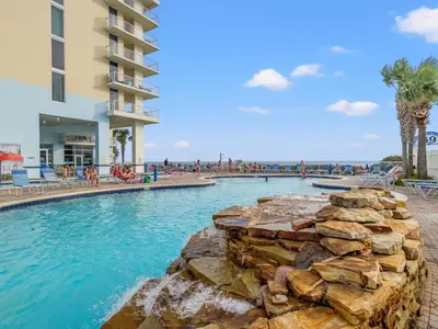 a swimming pool at a resort with people on the beach at Majestic Beach Towers #2-1203 in Panama City Beach