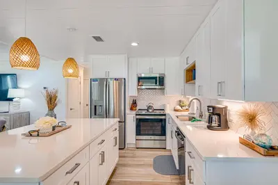 a kitchen with white cabinets and stainless steel appliances at Walk to Beach Chic PCB Getaway with Yard in Panama City Beach