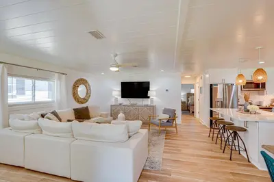 a living room with a white couch and a kitchen at Walk to Beach Chic PCB Getaway with Yard in Panama City Beach