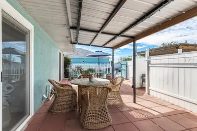 a patio with a table and chairs on a balcony at Shells Family Beach House Coastal Retreat with Private Pool Golf Cart & Steps to the Beach in Panama City Beach