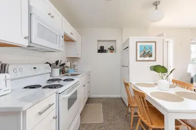 a kitchen with white appliances and a table with chairs at Shells Family Beach House Coastal Retreat with Private Pool Golf Cart & Steps to the Beach in Panama City Beach