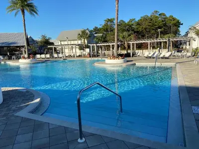 a large swimming pool with blue water and palm trees at BIG EASY on 30A in Watersound Beach