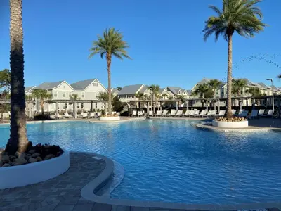 a large swimming pool with palm trees and houses at BIG EASY on 30A in Watersound Beach