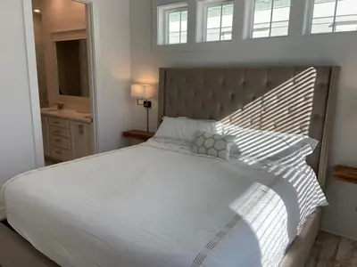 a bedroom with a large white bed with a large headboard at BIG EASY on 30A in Watersound Beach