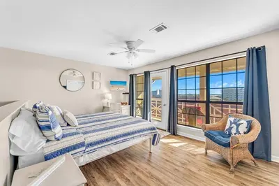 a bedroom with a bed and a chair and windows at Balconies with a View at Horizon South 54-302 in Panama City Beach