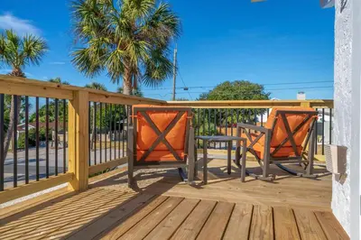 a deck with two chairs and a table at Casa Del Palms - Private Pool Home, Game Room, 2 Min Walk to Beach, Pets OK! in Panama City Beach