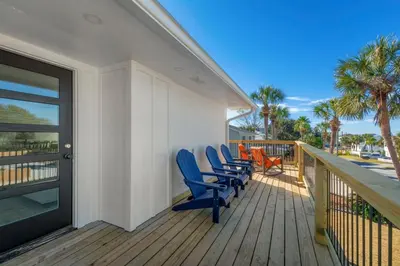 a deck with blue chairs and a balcony with palm trees at Casa Del Palms - Private Pool Home, Game Room, 2 Min Walk to Beach, Pets OK! in Panama City Beach