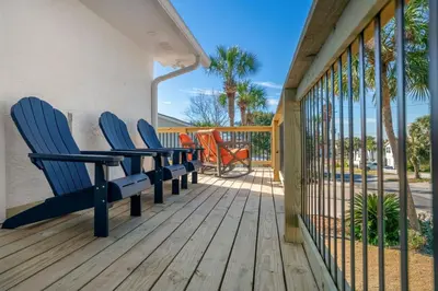 two blue chairs on a deck with palm trees at Casa Del Palms - Private Pool Home, Game Room, 2 Min Walk to Beach, Pets OK! in Panama City Beach
