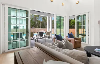 a living room with a couch and chairs and windows at Something Salty in Santa Rosa Beach