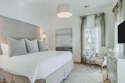 a white bedroom with a large bed and a chair at Southern Breeze in Inlet Beach