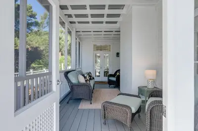 a porch with wicker chairs and a table at Southern Breeze in Inlet Beach