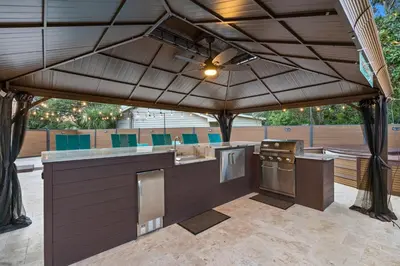 an outdoor kitchen with an umbrella on a patio at Sandcastle House Hot Tub, OD Kitchen & Game Room! in Panama City Beach