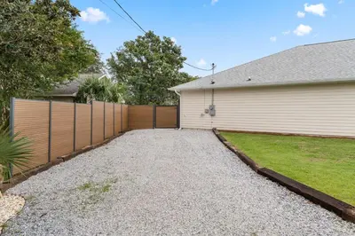 a driveway in front of a house with a fence at Sandcastle House Hot Tub, OD Kitchen & Game Room! in Panama City Beach