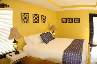a yellow bedroom with a bed and two lamps at Vibrant NewOrleans style retreat in Panama City Beach