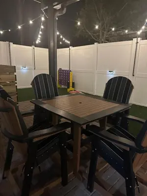 a wooden table with two chairs and a fence at Vibrant NewOrleans style retreat in Panama City Beach