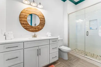 a white bathroom with a toilet and a mirror at Breezin at 19406 FBR in Panama City Beach