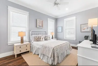 a bedroom with a bed and two lamps and windows at Breezin at 19406 FBR in Panama City Beach