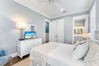 a white bedroom with a bed and a tv at Breezin at 19406 FBR in Panama City Beach