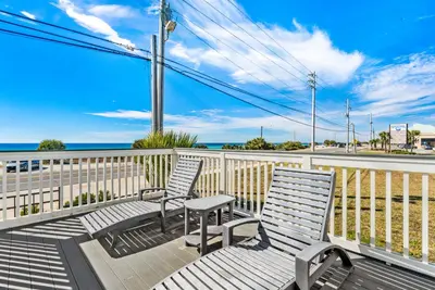 two chairs and a table on a balcony with the ocean at Breezin at 19406 FBR in Panama City Beach