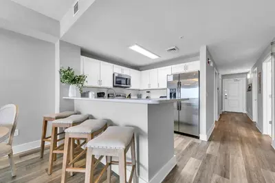 a kitchen with white cabinets and bar stools at Calypso 3-1107 in Panama City Beach
