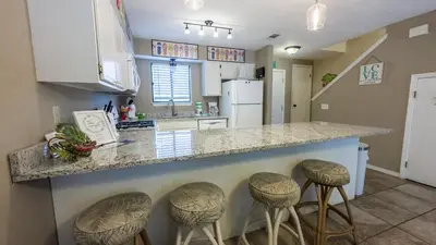 a kitchen with stools at a counter with a counter top at 2 BD 2 and half BA Two Story Beach Haven Pet Friendly with Golf Cart in Panama City Beach