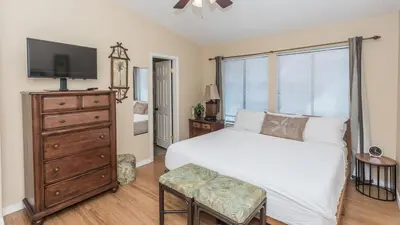 a bedroom with a bed and a dresser with a tv at 2 BD 2 and half BA Two Story Beach Haven Pet Friendly with Golf Cart in Panama City Beach