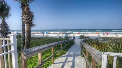 a path to the beach with a fence and palm trees at 2 BD 2 and half BA Two Story Beach Haven Pet Friendly with Golf Cart in Panama City Beach