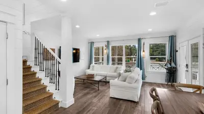 a living room with white walls and a staircase at Best of Both Worlds in Santa Rosa Beach
