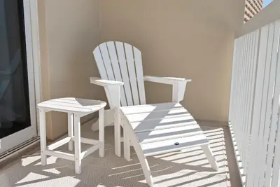 a white rocking chair and stool sitting on a porch at 1004 Seychelles in Panama City Beach