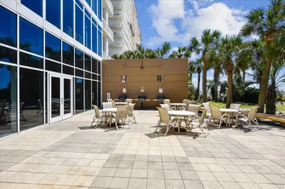 a patio with tables and chairs in front of a building at 1005 Sterling Beach in Panama City Beach