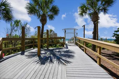 a wooden boardwalk with palm trees on the beach at 1005 Sterling Beach in Panama City Beach