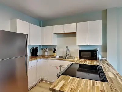 a kitchen with white cabinets and a stainless steel refrigerator at PC Beach Retreat D in Panama City Beach