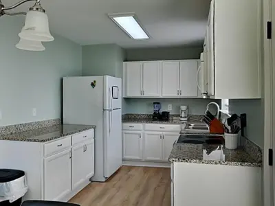 a kitchen with white cabinets and a white refrigerator at PC Beach Retreat D in Panama City Beach