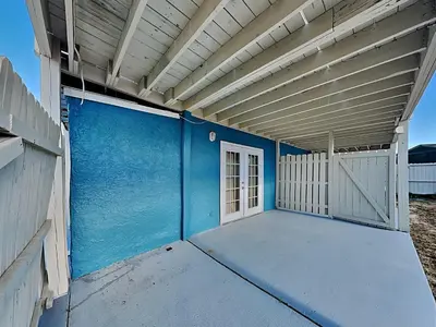 a blue building with a white door and a fence at PC Beach Retreat D in Panama City Beach