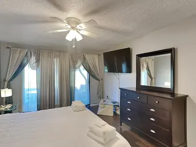 a bedroom with a bed with a ceiling fan and a mirror at Edgewater Villa #2005 in Panama City Beach