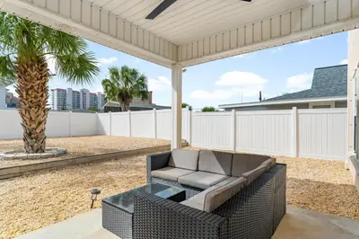 a patio with a couch and a palm tree at Beach House - Sunset Escape by Panhandle Getaways in Panama City Beach