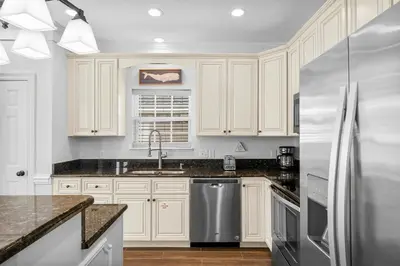 a kitchen with white cabinets and a stainless steel refrigerator at Beach House - Sunset Escape by Panhandle Getaways in Panama City Beach