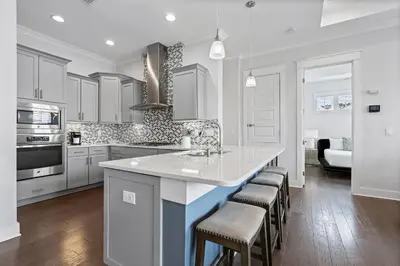 a kitchen with white cabinets and a island with bar stools at The Anchorage in Inlet Beach