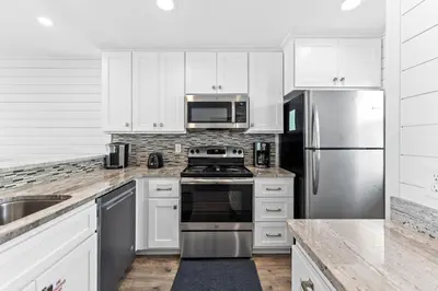 a kitchen with white cabinets and stainless steel appliances at Ramsgate Harbour #16 by 30A Escapes in Panama City Beach