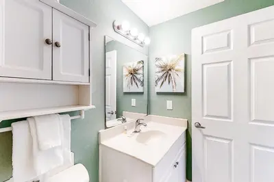 a white bathroom with a sink and a mirror at Breathtaking gulf-front condo near Pier Park in Panama City Beach
