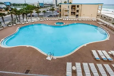 a large swimming pool with chairs and the ocean at Breathtaking gulf-front condo near Pier Park in Panama City Beach