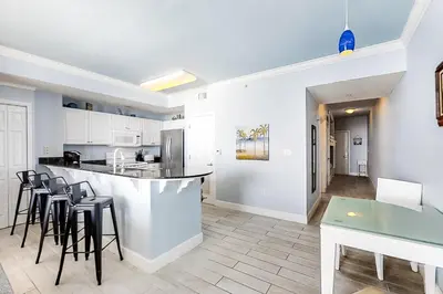a kitchen with a bar with stools and a table at Breathtaking gulf-front condo near Pier Park in Panama City Beach