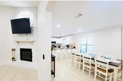a living room with a fireplace and a table and chairs at Stunning 4BD Jacuzzi - 4 Min To Beach Panama City in Panama City Beach