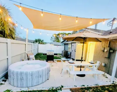 a patio with a table and an umbrella at Stunning 4BD Jacuzzi - 4 Min To Beach Panama City in Panama City Beach